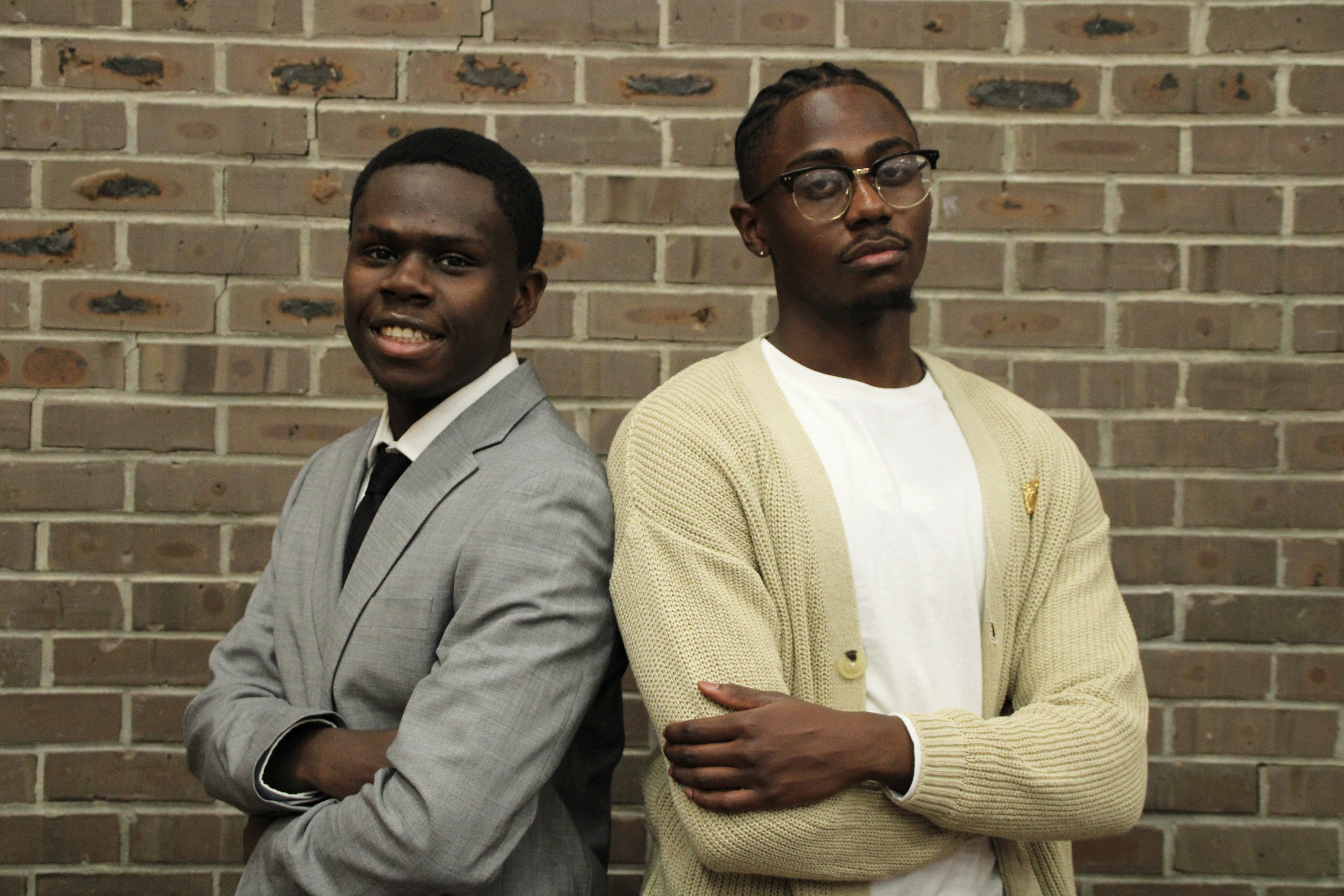 Two black male students standing shoulder to shoulder against a Brick Wall at Rutgers New Brunswick campus